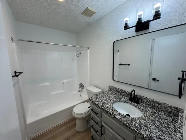 a bathroom with a granite countertop sink toilet and shower