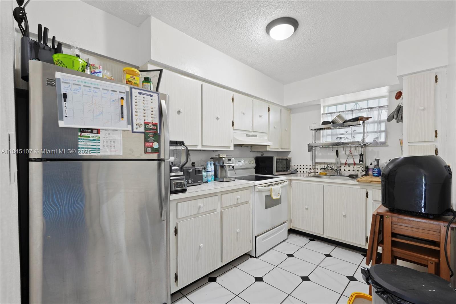 2498 Southwest 17th Avenue, Unit 4311 Miami, FL 33133 - Photo 5 of 19 a kitchen with white cabinets and refrigerator