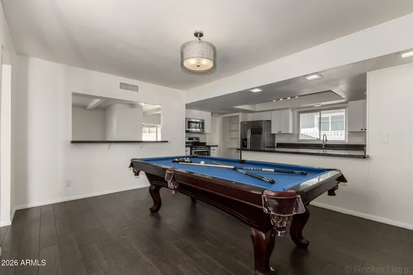 a room with wooden floor pool table and windows
