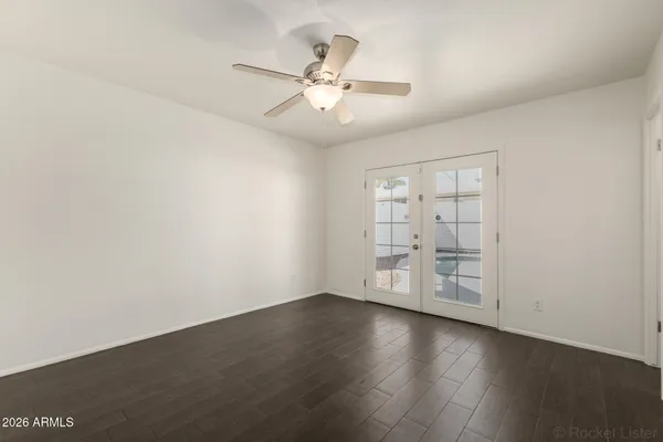 an empty room with wooden floor fan and windows