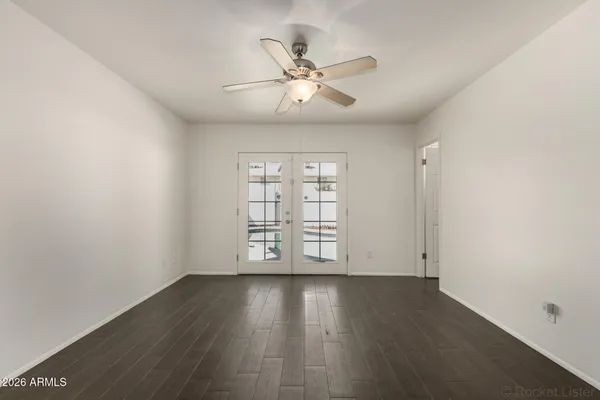 an empty room with wooden floor fan and windows