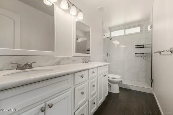 a bathroom with a granite countertop toilet sink and mirror