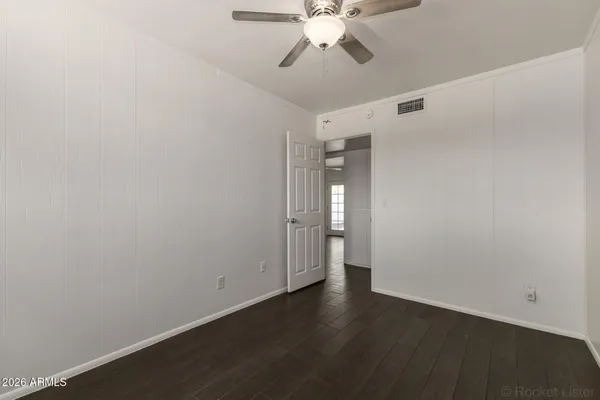 an empty room with wooden floor fan and window