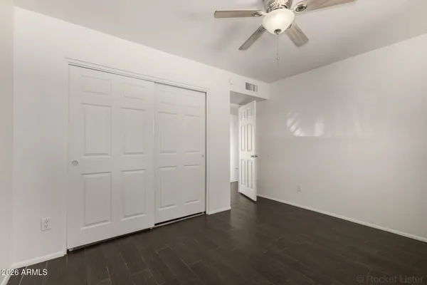 an empty room with wooden floor fan and windows