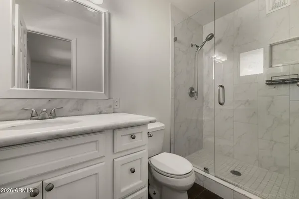 a bathroom with a granite countertop sink toilet and shower