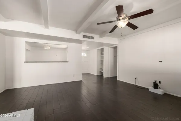 a view of an empty room with wooden floor and a ceiling fan