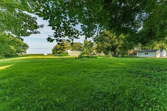 a view of a house next to a big yard and large trees