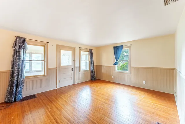 an empty room with wooden floor and windows