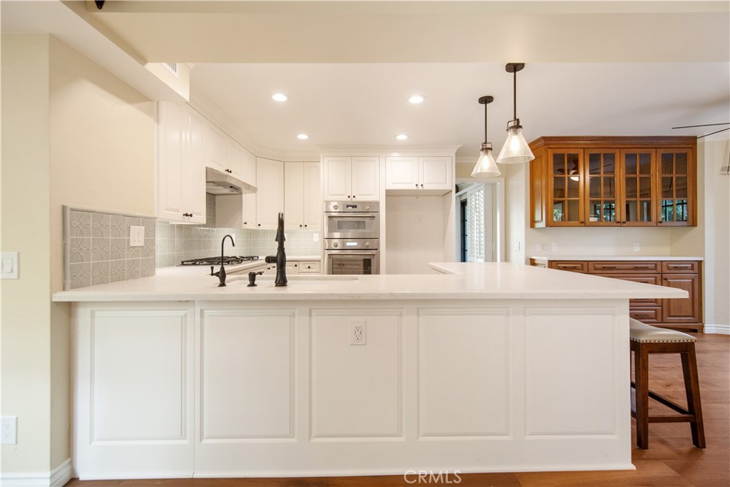 24965 Danamaple Dana Point, CA 92629 - Photo 6 of 72 a kitchen with stainless steel appliances kitchen island granite countertop a stove a sink and white cabinets with wooden floor