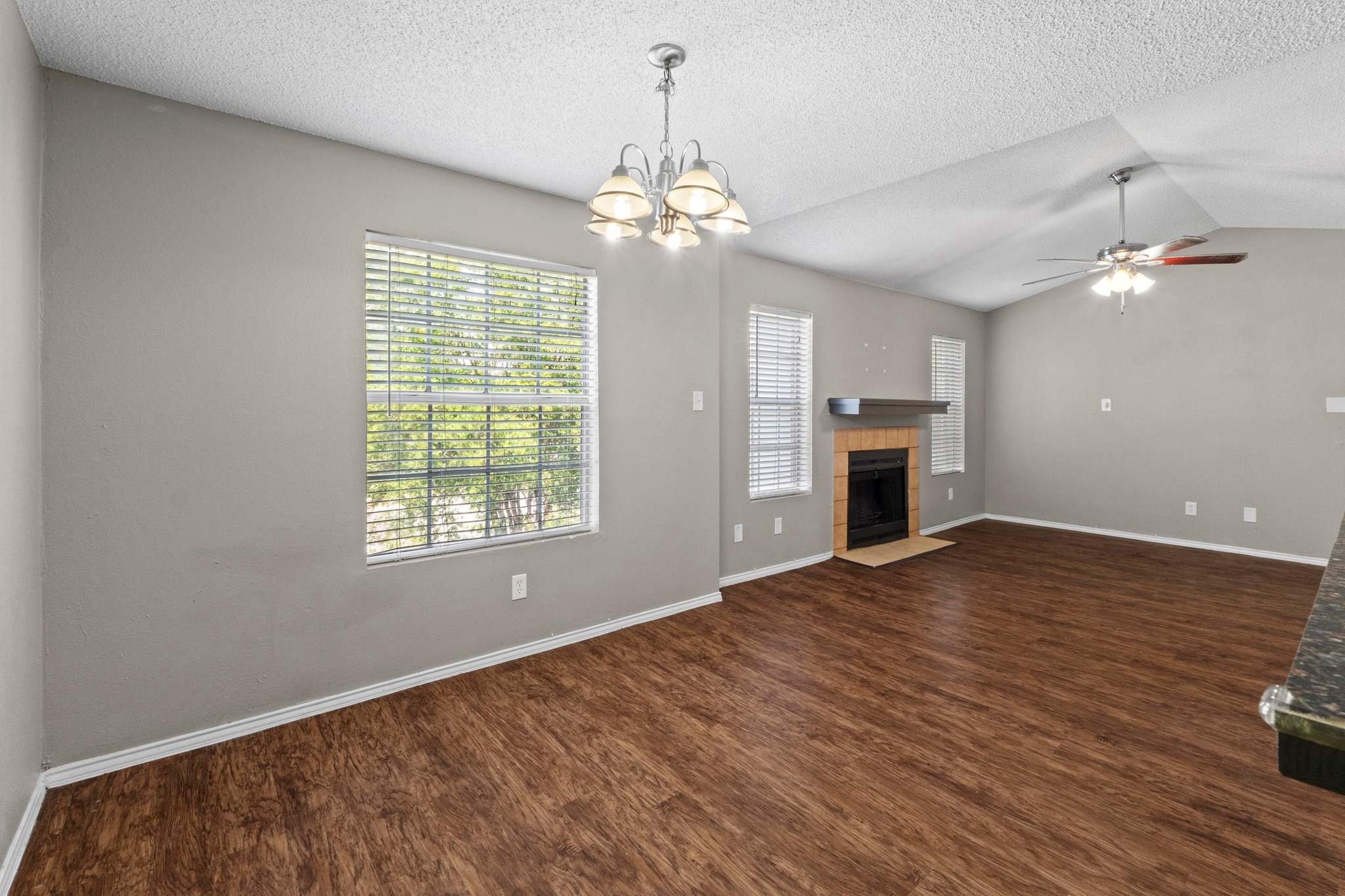 4208 Duval Road, Unit C Austin, TX 78759 - Photo 12 of 28 Unfurnished living room with healthy amount of natural light, a ceiling fan, wood finished floors, lofted ceiling, and a textured ceiling