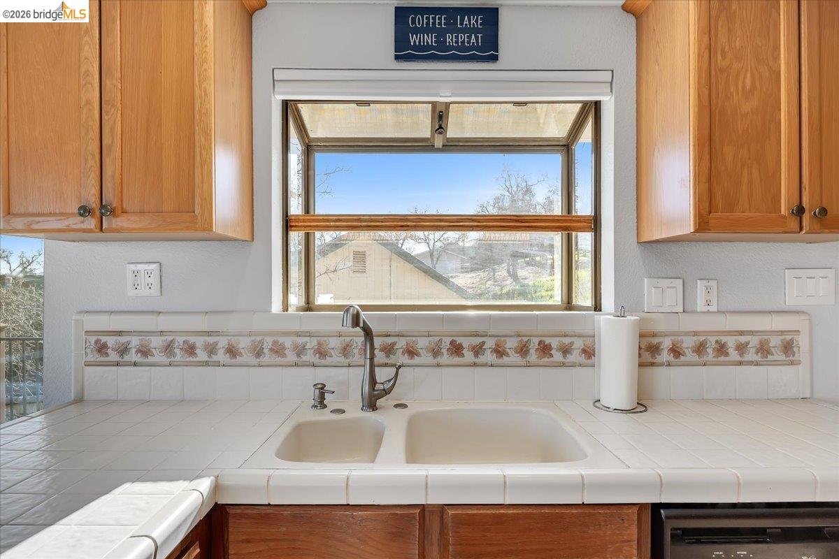 4620 Bayview Drive Copperopolis, CA 95228 - Photo 17 of 59 Kitchen featuring tile countertops, brown cabinetry, plenty of natural light, and dishwasher