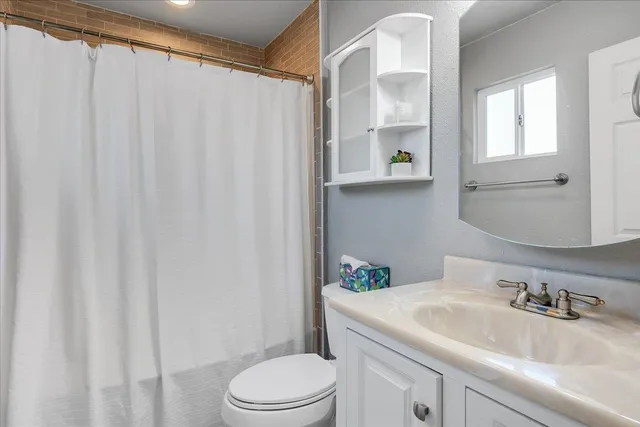 a bathroom with a granite countertop sink a toilet and a window