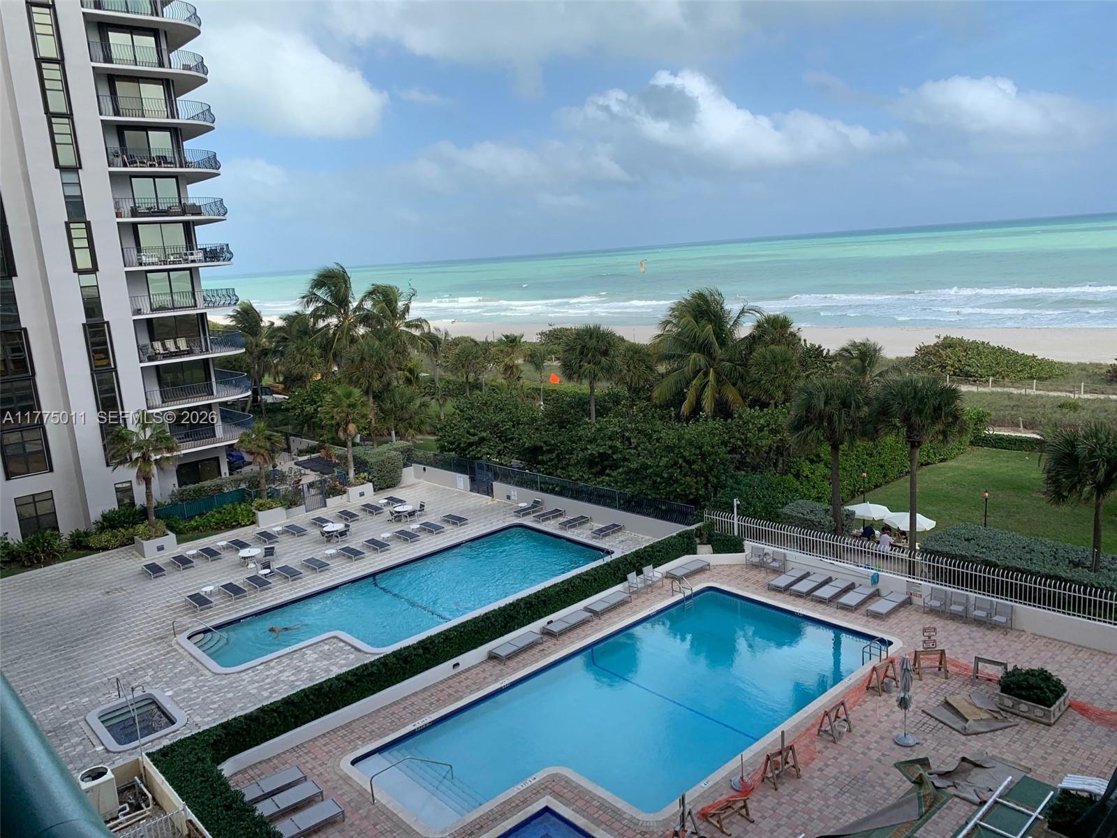 8855 Collins Avenue, Unit 5B Surfside, FL 33154 - Photo 2 of 35 a view of a pool with lawn chairs and a yard