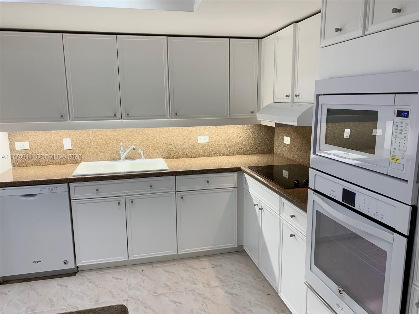 8855 Collins Avenue, Unit 5B Surfside, FL 33154 - Photo 8 of 35 a kitchen with granite countertop white cabinets and sink