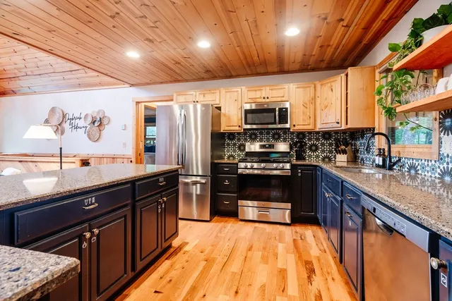 a large kitchen with stainless steel appliances wooden cabinets a sink and a stove