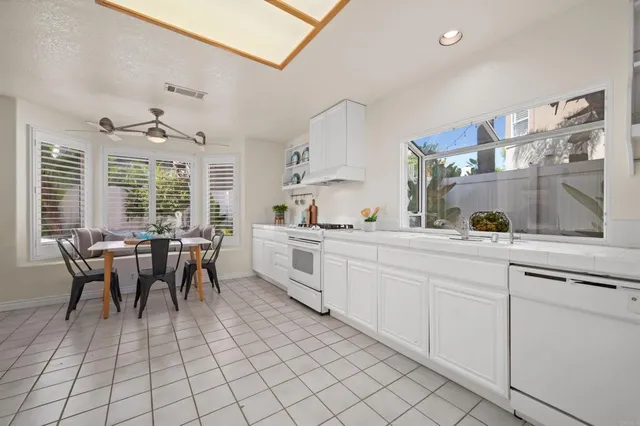 a large white kitchen with cabinets furniture and a dining table