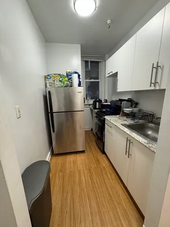 a kitchen with a refrigerator a sink and white cabinets