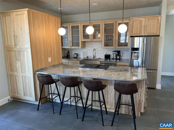a kitchen with stainless steel appliances granite countertop wooden cabinets a dining table and chairs