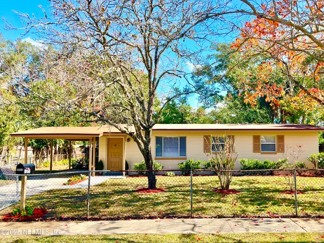 a view of house with yard and tree in front of it