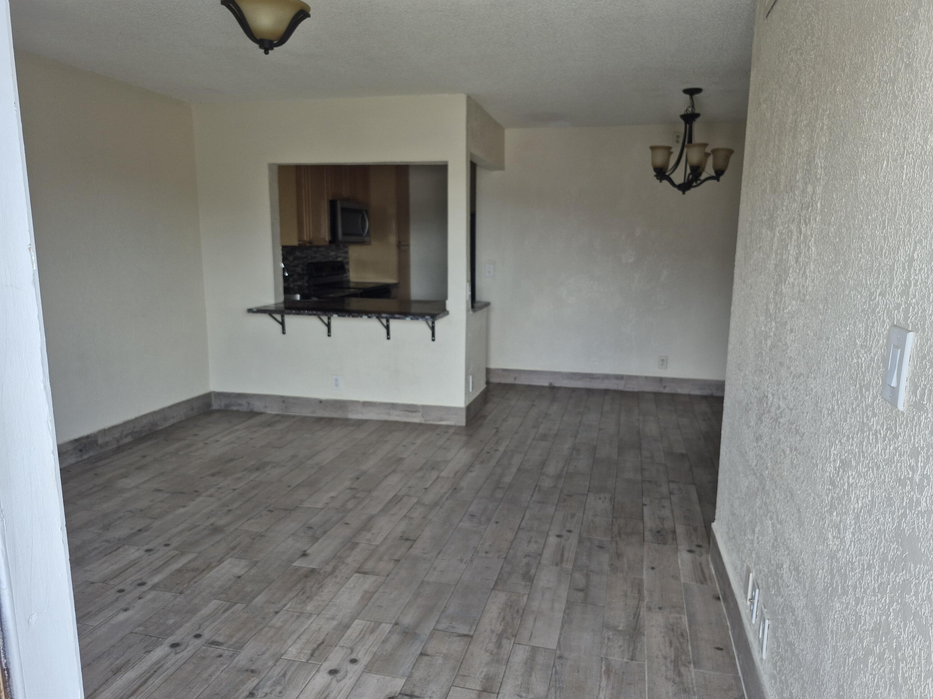 10039 Winding Lake Road, Unit 202 Sunrise, FL 33351 - Photo 5 of 14 a view of a livingroom with wooden floor and a ceiling fan