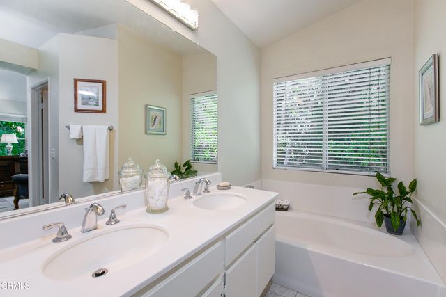 a bathroom with a bathtub a sink a window and a mirror