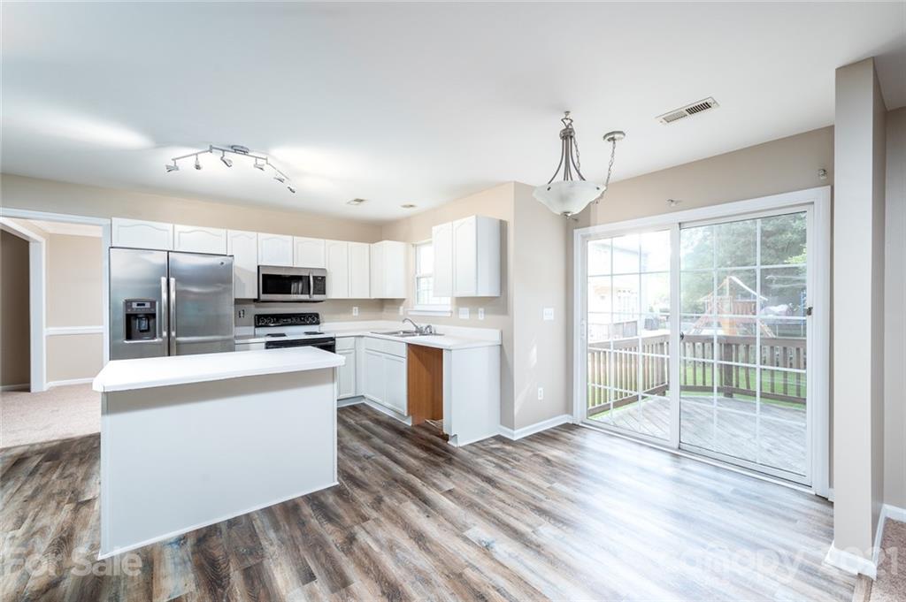 840 Knightsbridge Road Fort Mill, SC 29708 - Photo 5 of 32 a kitchen with stainless steel appliances kitchen island granite countertop a stove top oven a sink dishwasher a refrigerator and white cabinets with wooden floor