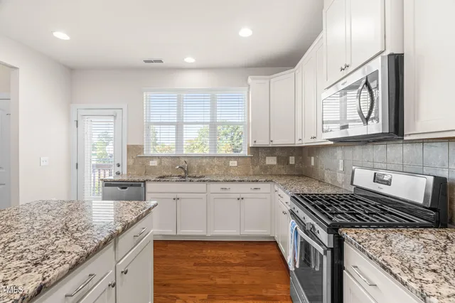 a kitchen with stainless steel appliances granite countertop a stove a sink and a microwave
