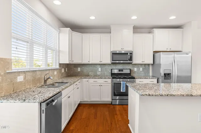 a kitchen with stainless steel appliances granite countertop a sink stove microwave and refrigerator