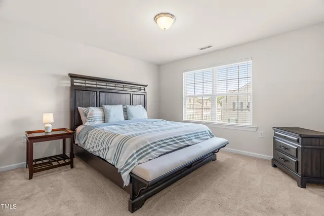 a bedroom with a bed and a lamp on dresser