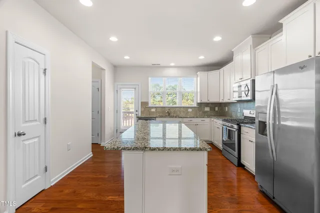 a kitchen with granite countertop a refrigerator and a stove top oven
