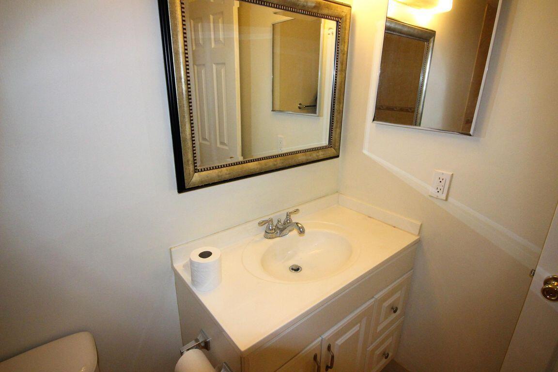 8801 West Sample Road, Unit 11 Coral Springs, FL 33065 - Photo 17 of 25 a bathroom with a sink and mirror with toilet