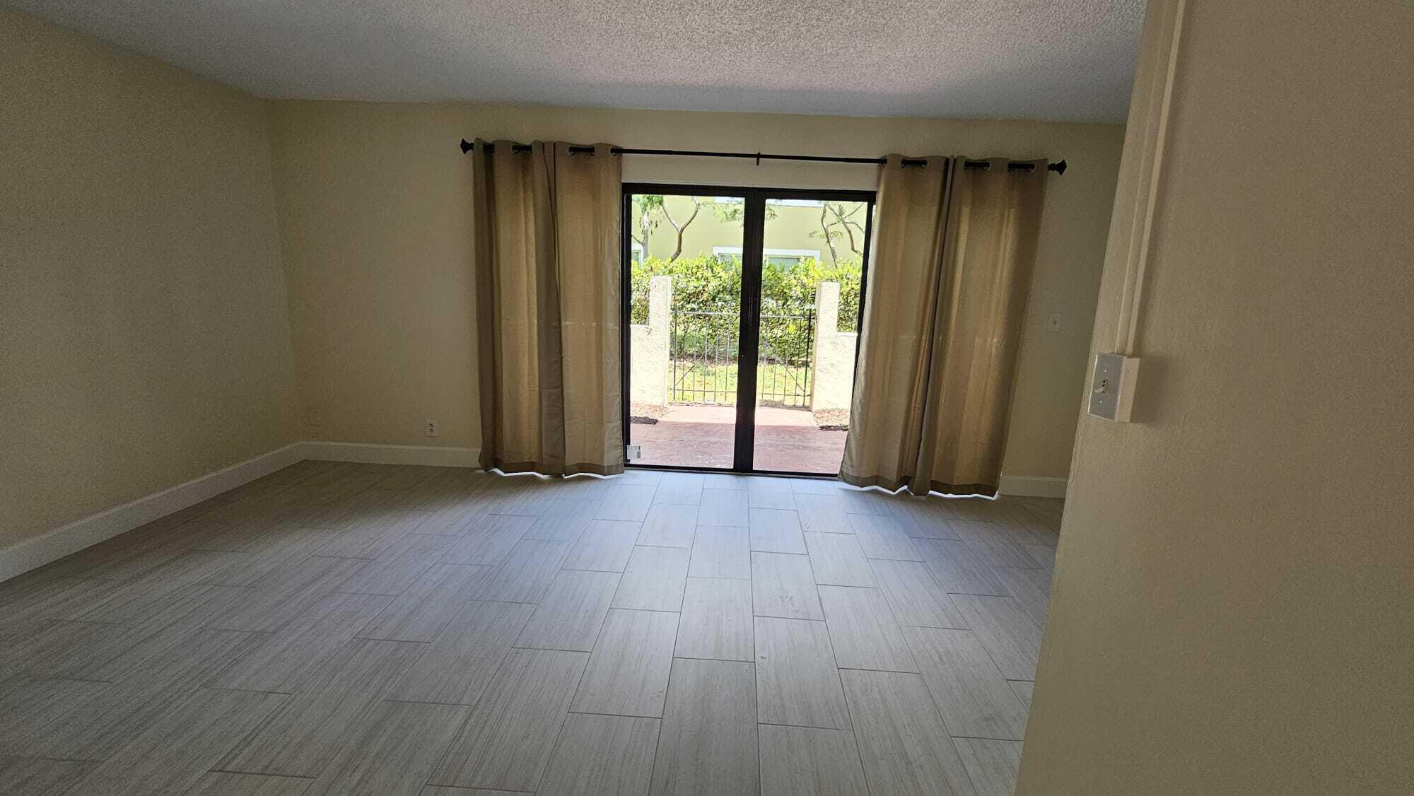 8801 West Sample Road, Unit 11 Coral Springs, FL 33065 - Photo 4 of 25 an empty room with wooden floor and windows