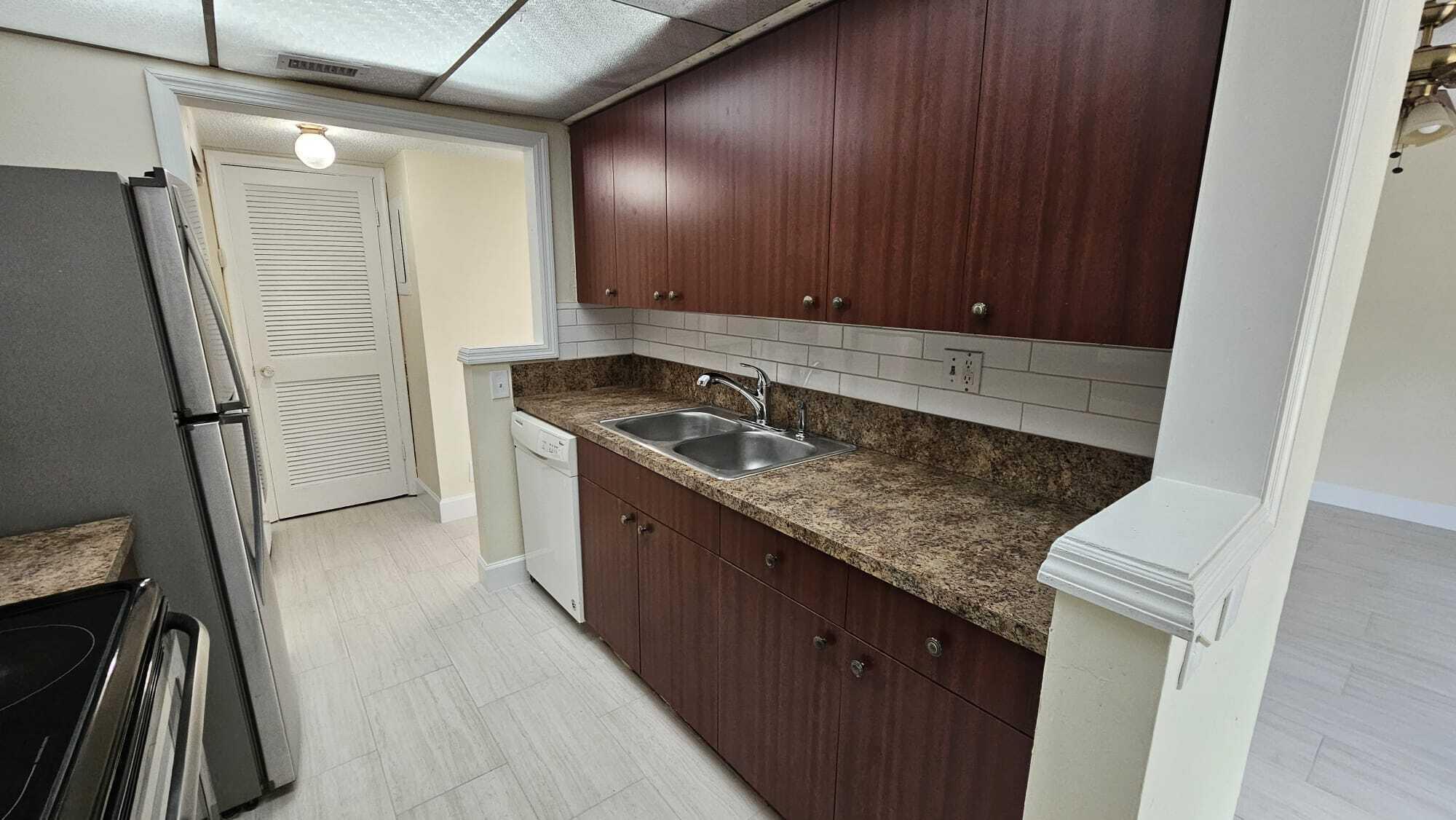 8801 West Sample Road, Unit 11 Coral Springs, FL 33065 - Photo 6 of 25 a kitchen with granite countertop sink stove and cabinets