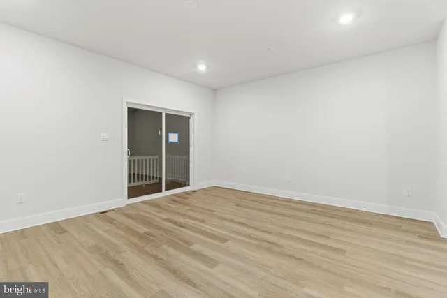 an empty room with wooden floor and natural light