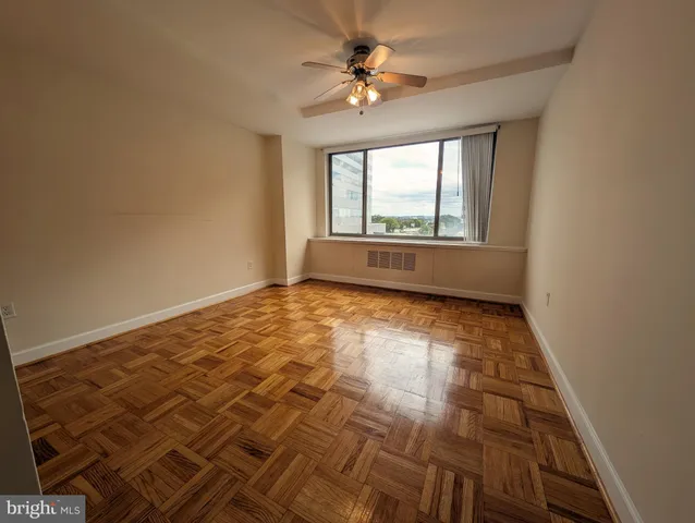 a view of an empty room and chandelier fan