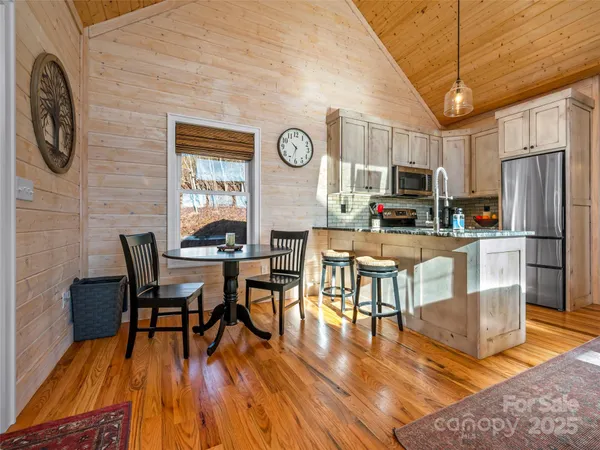 a kitchen with stainless steel appliances granite countertop a stove a refrigerator a kitchen island a dining table and chairs