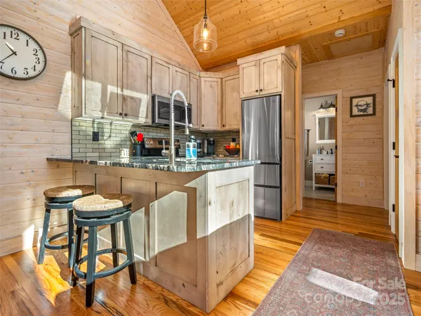 a kitchen with stainless steel appliances granite countertop a stove a refrigerator a oven with white cabinets and couches