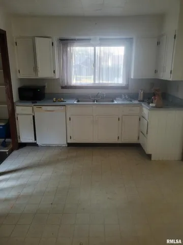 a kitchen with granite countertop white cabinets and a sink