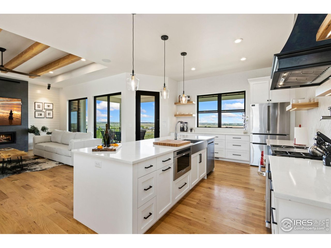 3802 Bridle Ridge Circle Severance, CO 80524 - Photo 13 of 50 a large kitchen with stainless steel appliances kitchen island granite countertop a stove a sink dishwasher and white cabinets with wooden floor