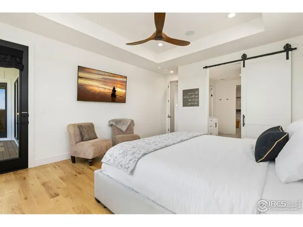 a bedroom with a bed a couch and a flat tv screen on the dresser