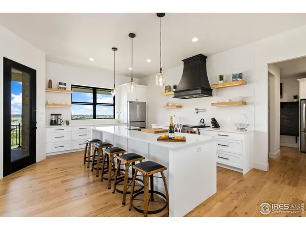 a kitchen with stainless steel appliances kitchen island wooden floors stove and white cabinets