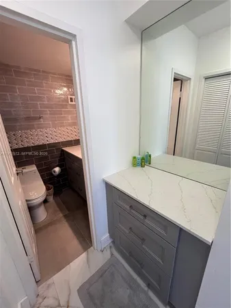 a bathroom with a granite countertop sink a toilet and a mirror