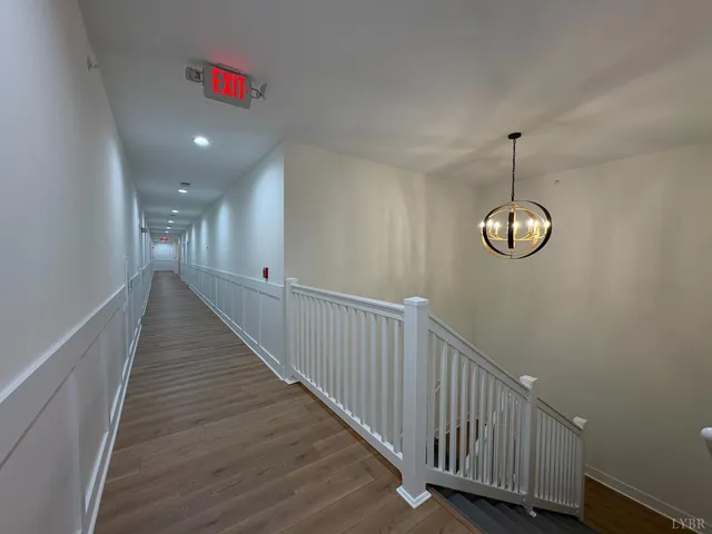 a view of a hallway with wooden floor and stairs