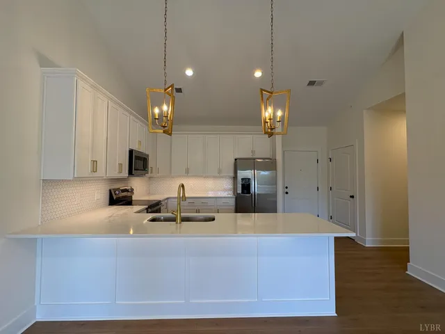 a kitchen with kitchen island granite countertop a sink cabinets and stainless steel appliances