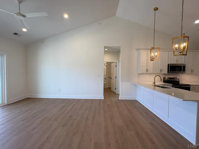 a large kitchen with granite countertop a stove a sink a center island and wooden floor