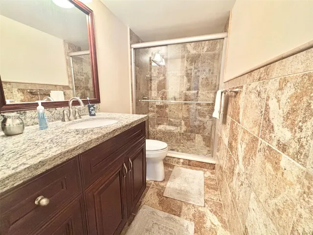 a bathroom with a granite countertop sink toilet and shower