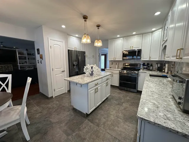 a kitchen with kitchen island granite countertop a sink counter top space appliances and cabinets