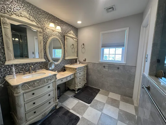 a spacious bathroom with a double vanity sink a mirror and a shower