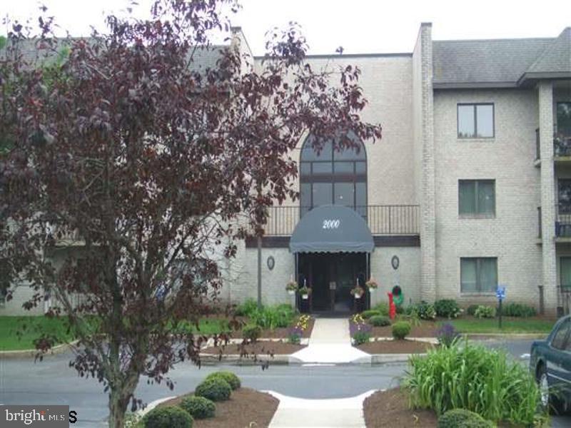 a front view of a house with garden and trees