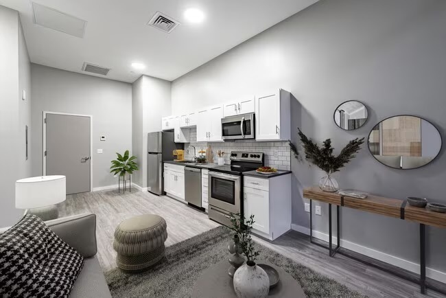 a living room with furniture a clock and a view of kitchen